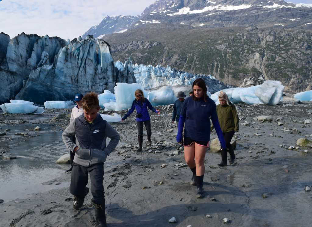 Family on shore walk by Lamplugh Glacier in Alaska