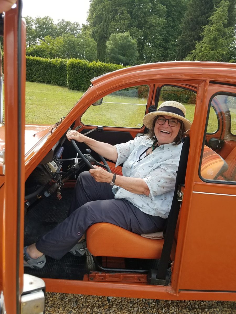 Cynthia in an orange vintage Citroen 2CV on a canal du midi cruise