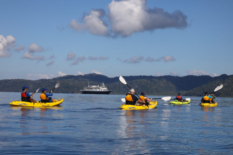 Kayakers in Alaska on an UnCruise with Safari Voyager in the background