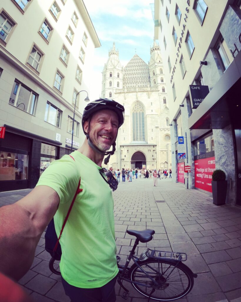 John cycling in Vienna and stopping for a selfie in front of St. Stephen’s Cathedral.